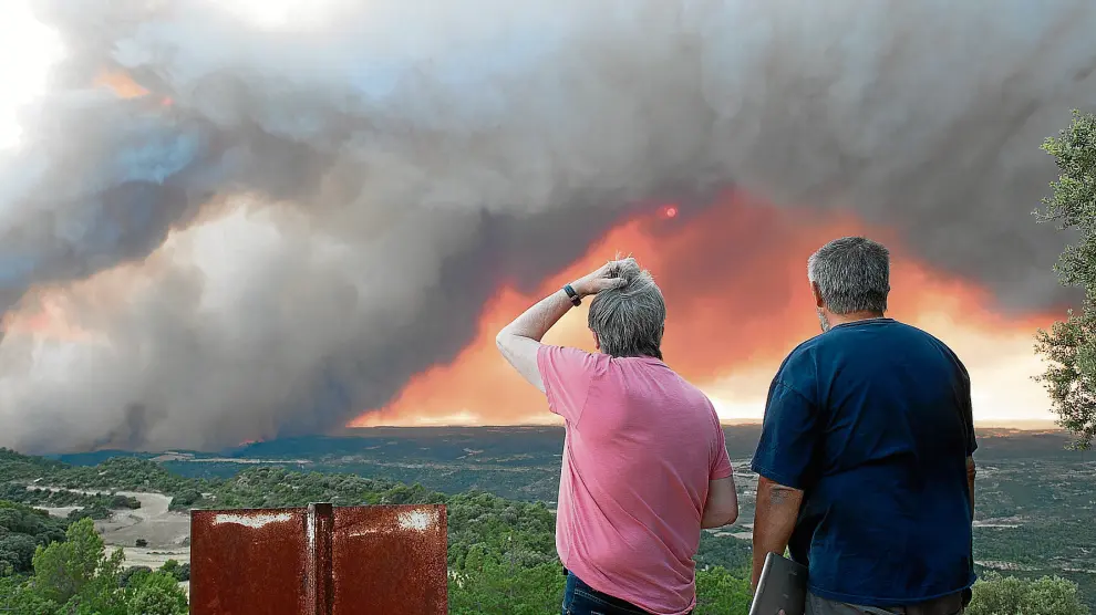 Dos vecinos de la zona afectada contemplan desolados el avance del incendio desde lo alto del pico El Fragal.