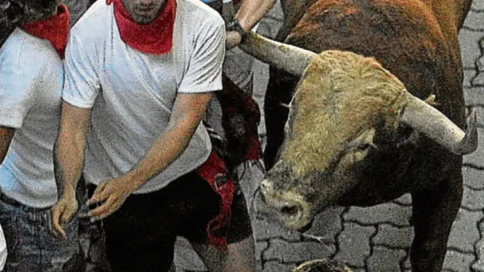 Uno de los toros engancha a un joven de la camiseta.