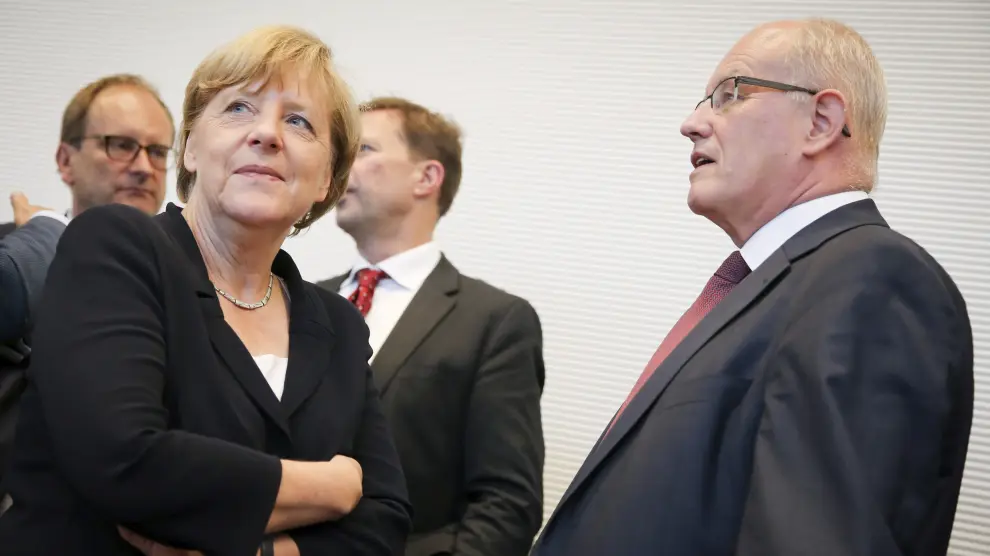 La canciller alemana, Angela Merkel, conversa con el jefe del grupo parlamentario conservador durante la reunión del lunes por la tarde.