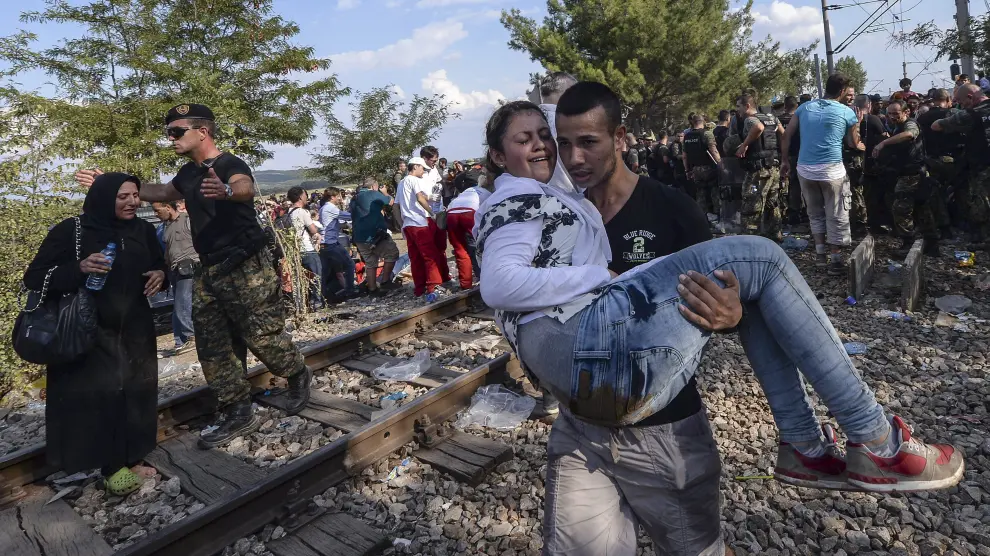 Dos inmigrantes cruzan el cordón de fuerzas especiales para llegar a Grecia en Gevgelija, Macedonia.
