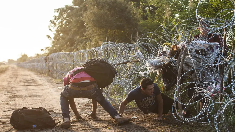 Varios inmigrantes pasan la alambrada que separa Serbia de Hungría