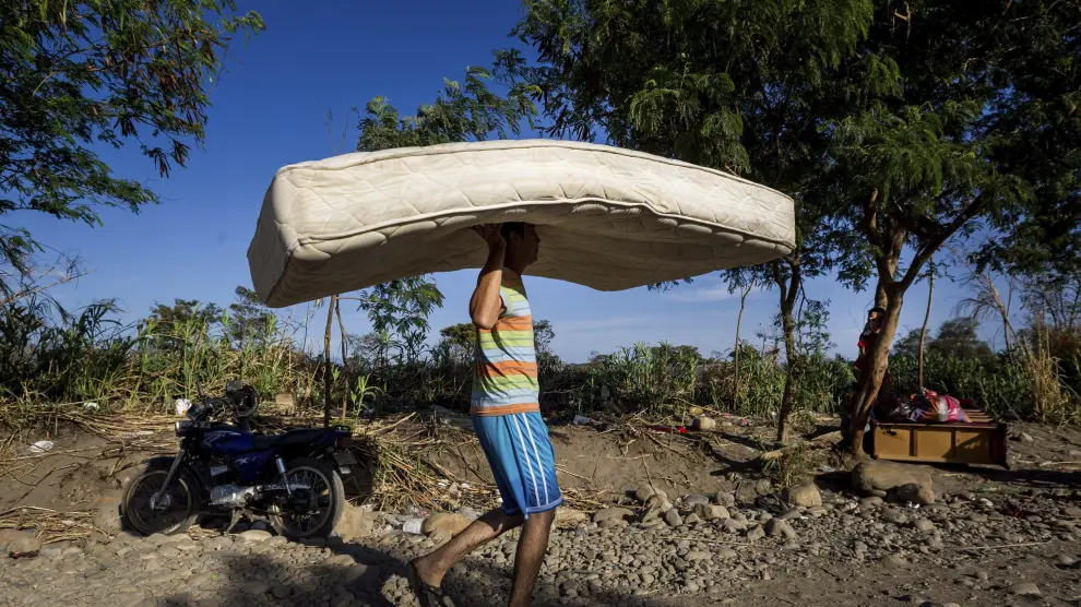Un hombre carga con un colchón por una trocha del sector "La Parada" tras cruzar el río Tachira.