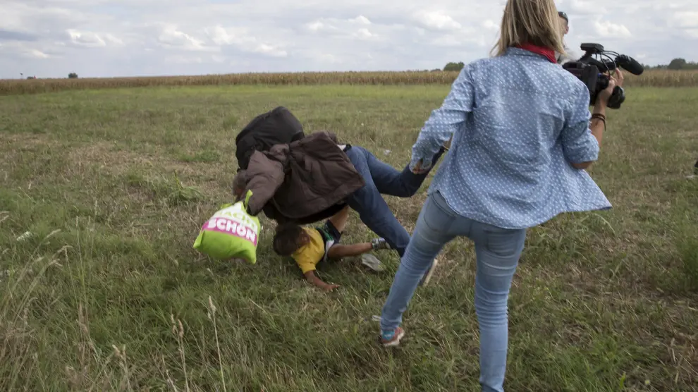 La reportera Petra László poniendo la zancadilla a un refugiado con su hijo.