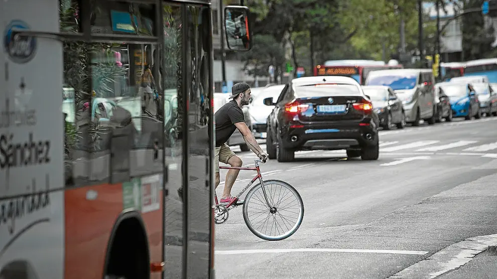 Un ciclista en el paseo de María Agustín, entre coches y autobuses.