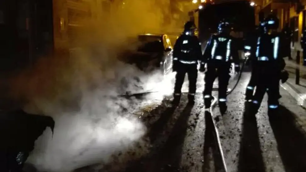 Los Bomberos de Zaragoza sofocando las llamas en cinco contenedores de la calle Pano y Ruata.