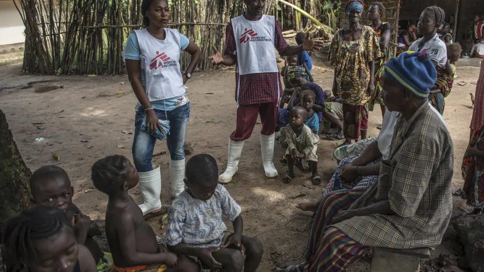 Dos miembros de Médicos Sin Fronteras hablan con ciudadanos de una aldea.