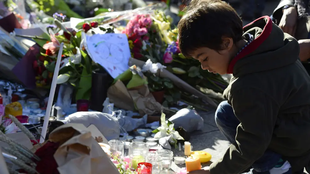 Un niño deposita un ramo de flores en uno de los lugares de los atentados