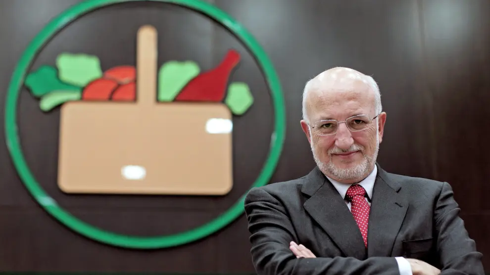El presidente de Mercadona, Juan Roig, posa junto al logo del supermercado