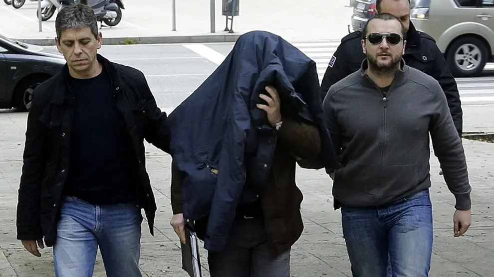 El profesor denunciado por abusos sexuales entra tapado en los juzgados de Barcelona acompañado por dos Mossos de paisano.