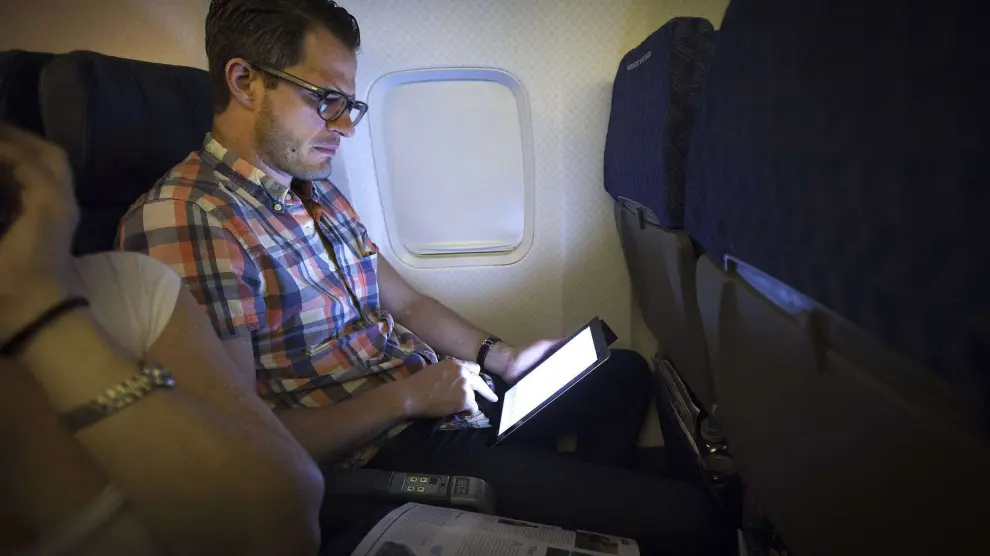 Un pasajero utilizando una tableta durante un viaje a bordo de un avión