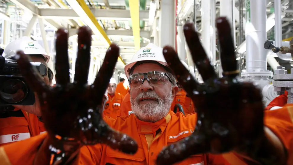 Fotografía de archivo fechada el 28 de octubre de 2010 que muestra al entonces presidente brasileño Luiz Inácio da Silva con las manos impregnadas de petróleo durante el lanzamiento de la plataforma de Petrobras