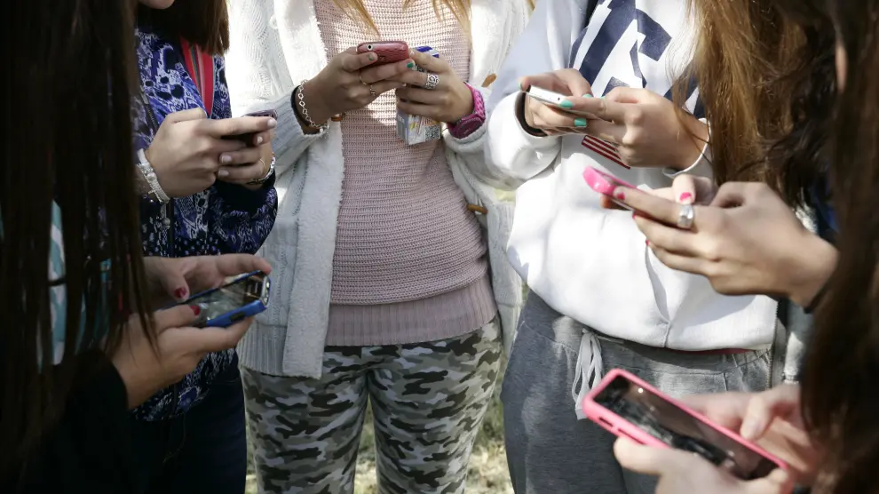 Menores utilizando sus teléfonos móviles.
