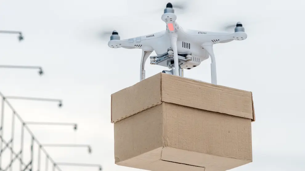 Un dron transporta una caja en un almacén logístico.