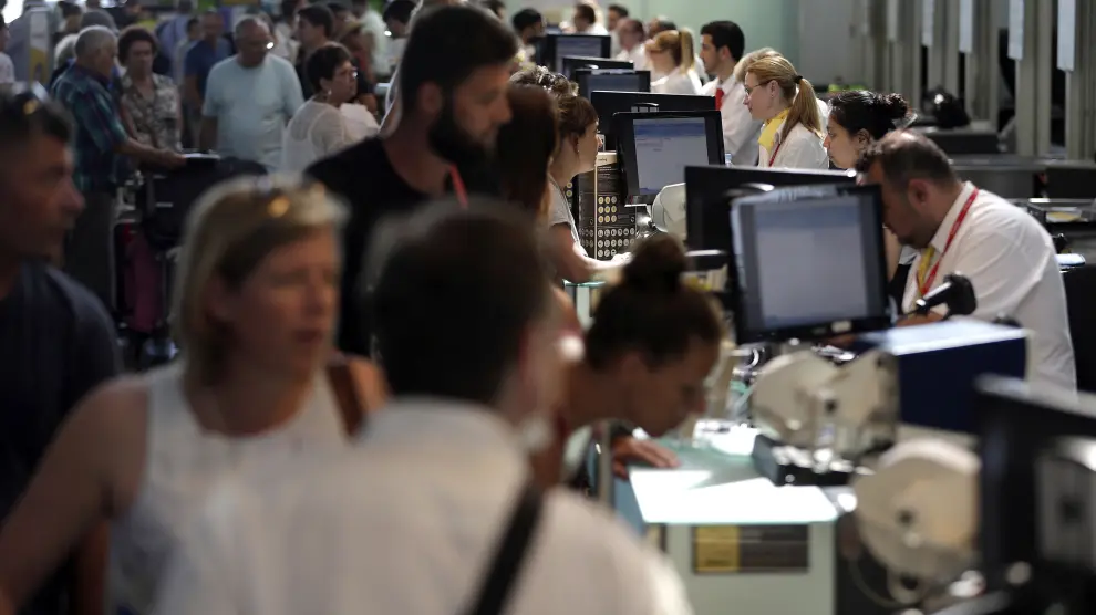 Personal de facturación de Vueling atiende a los viajeros en el Aeropuerto de El Prat este sábado.