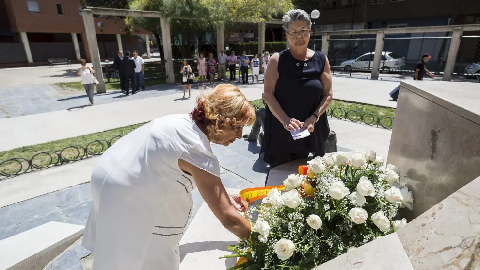 Marta Berdor, de blanco, y María Gracia Roca, colocan flores en el monumento de la casa cuartel.
