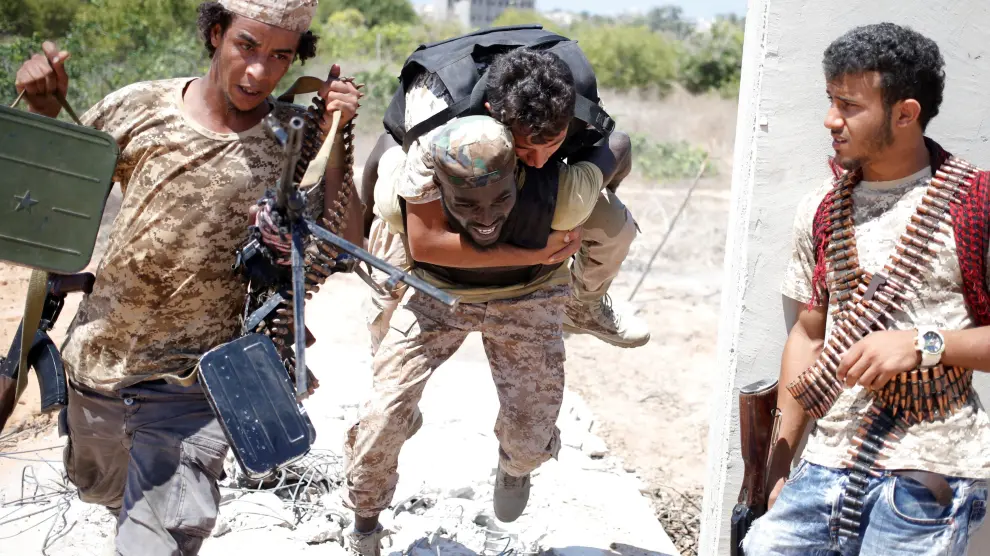Un soldado del régimen sirio carga con un compañero herido por el Estado Islámico en la zona que bombardea EE.UU.