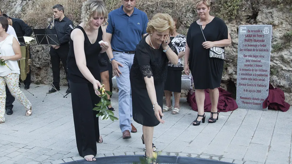 La hermana de Marina Okarynska y la madre de Laura del Hoyo depositan flores sobre el memorial en su recuerdo.