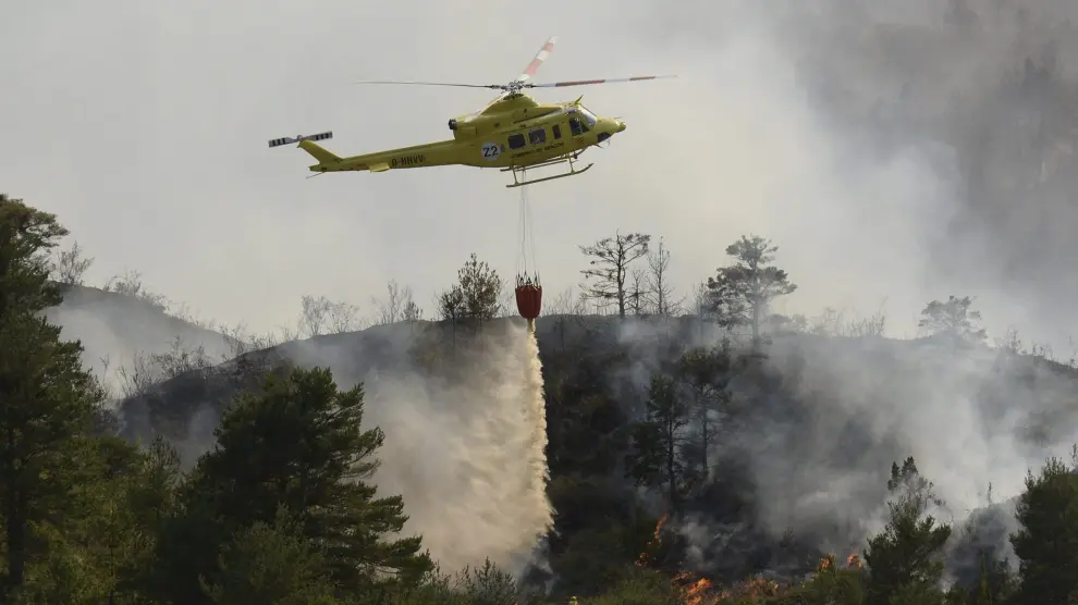 Un helicóptero suelta agua para sofocar el fuego que había llegado a los barrancos en Atarés .