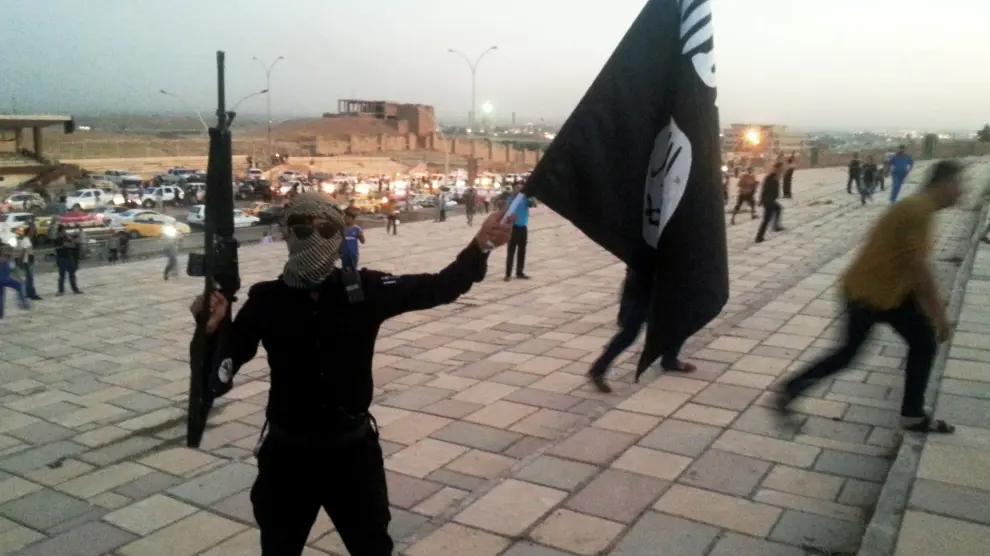 Un combatiente del Estado Islámico sostiene un arma y una bandera en la ciudad iraquí de Mosul.