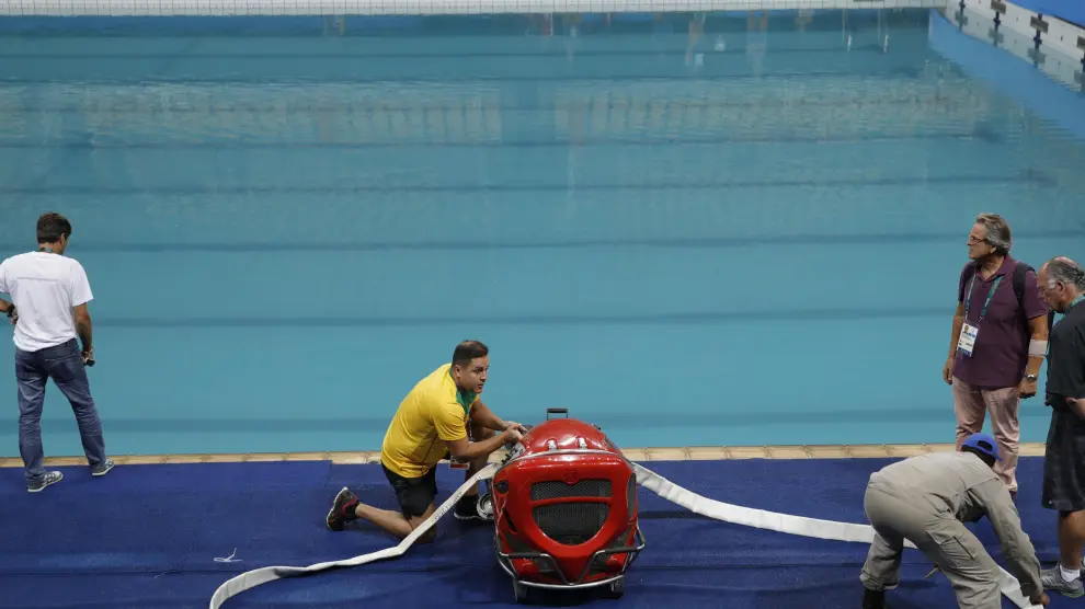 Los operarios cambian el agua de la piscina de calentamiento a la de competición