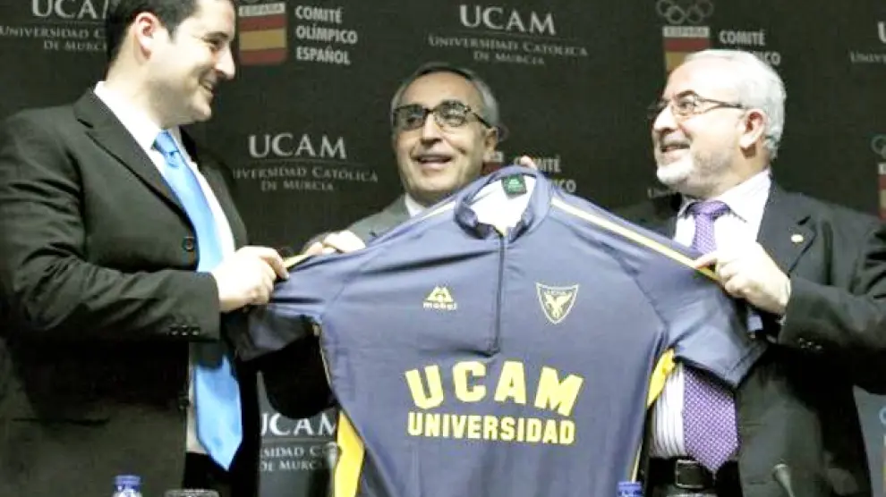 José Luis Mendoza (a la derecha), presidente de la UCAM, entrega una camiseta de su club al piragüista olímpico David Cal (izda.) en presencia de Alejandro Blanco (centro), presidente del Comité Olímpico Español.
