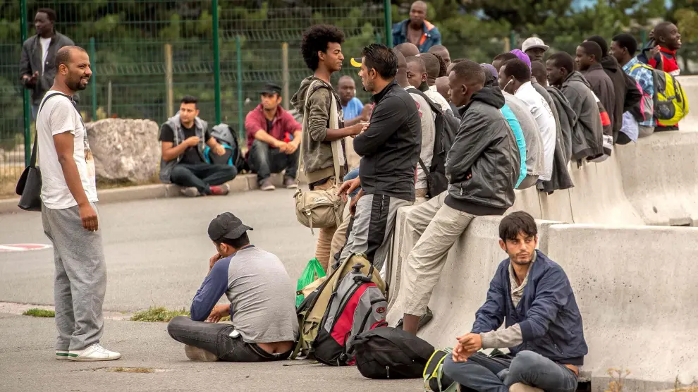 Varios refugiados del campo de Calais esperan para ser trasladados.
