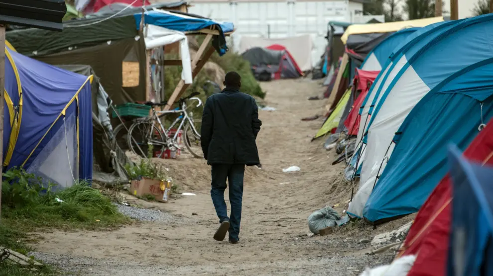 Un migrante camina en por el campamento de Calais, al norte de Francia