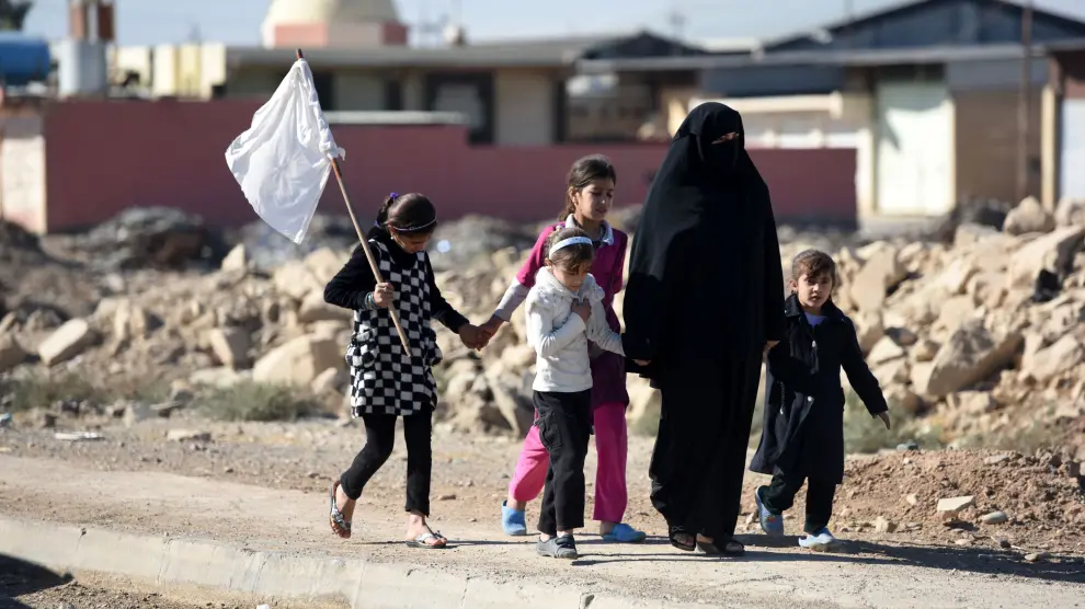Una mujer y varios niños intentan dejar Mosul alzando una bandera blanca.