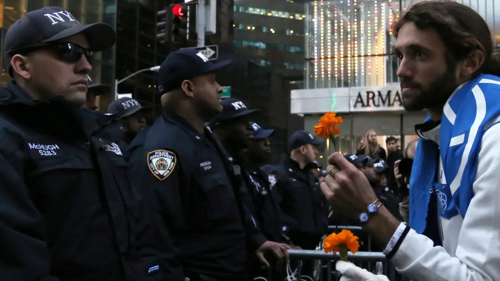 Uno de los manifestantes en protesta por Trump tiende una flor a los policías desplegados en Manhattan.