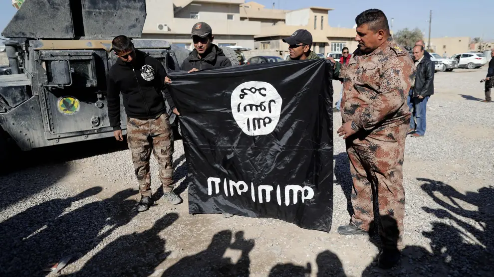 Soldados del Ejército de Iraq sostienen una bandera del Estado Islámico puesta al revés