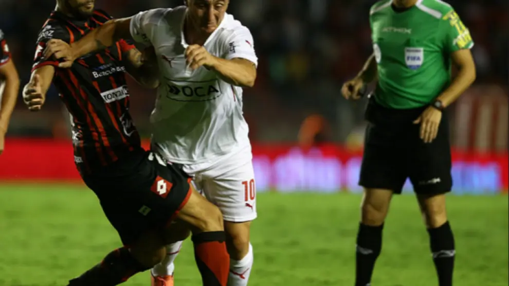 Jonathan Ferrari, con el uniforme rojo y negro del Patronato de Paraná, su actual equipo, intenta frenar a un rival del Independiente de Avellaneda en un partido de la liga argentina.