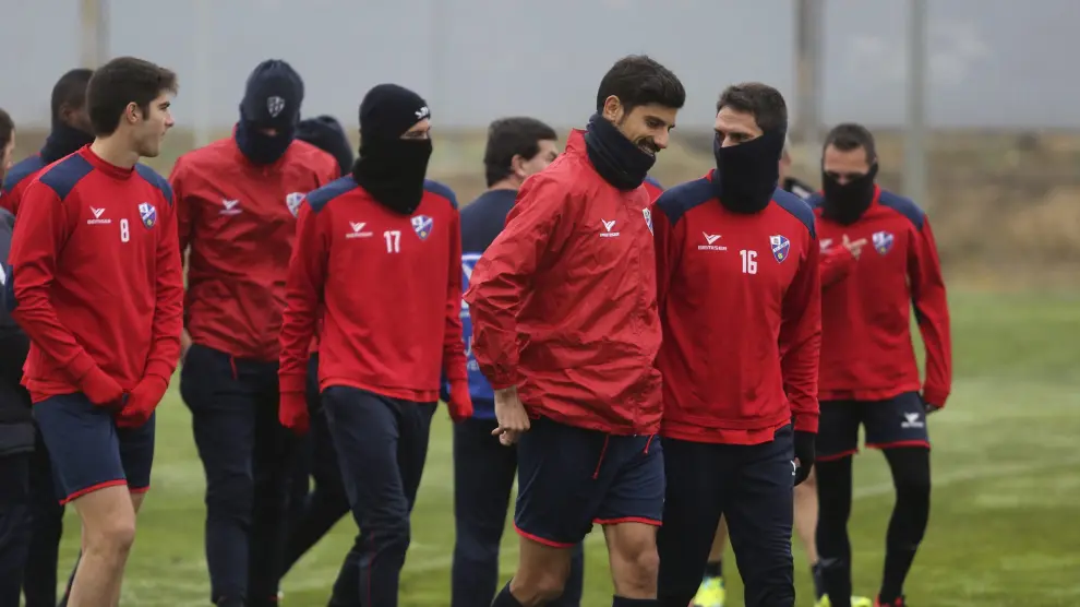 Los futbolistas del Huesca dialogan durante el inicio de una sesión de entrenamiento de la presente temporada.