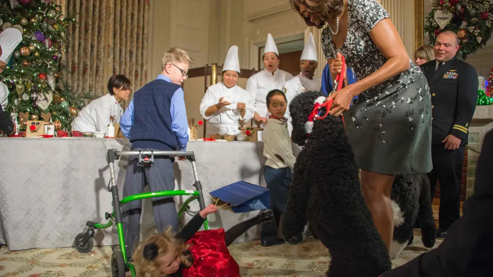 Michelle Obama sujeta a su perro Sunny después de que este derribara a una niña, en la Navidad de 2013.