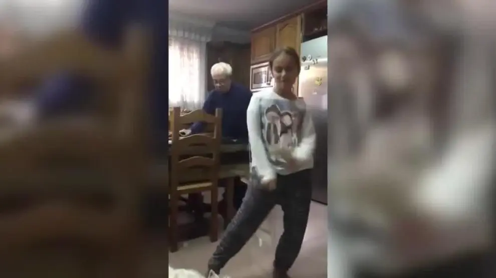 Una niña bailando mientras su abuelo le trolea