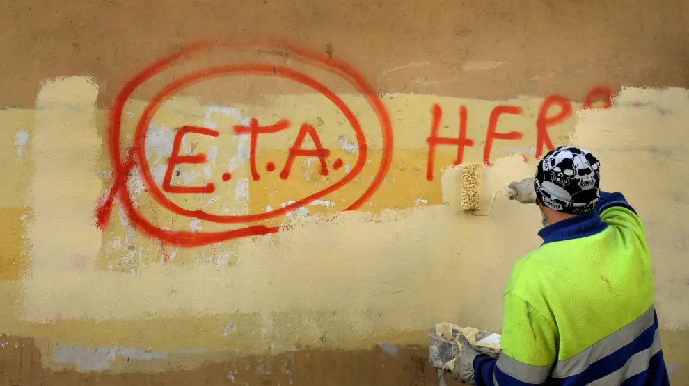 Un operario borra una pintada sobre ETA.