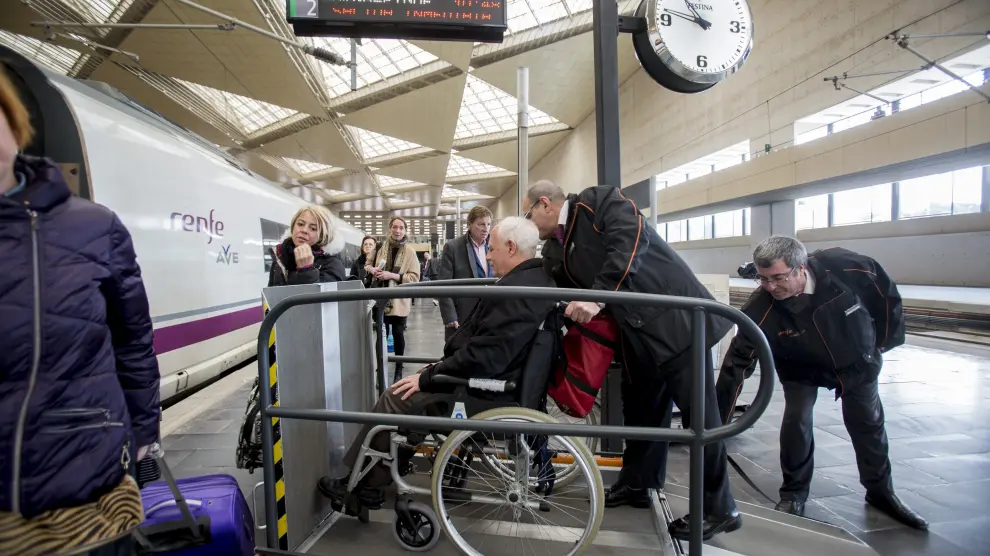 Personal de Atendo ayudan a una persona en silla de ruedas a acceder al tren en la estación de Delicias.