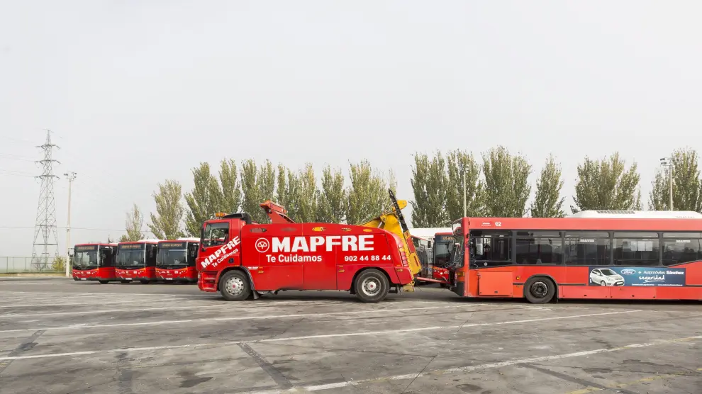 Una grúa con un autobús averiado pasa por delante de los once nuevos vehículos que se incorporaron a la flota el pasado mes de noviembre.