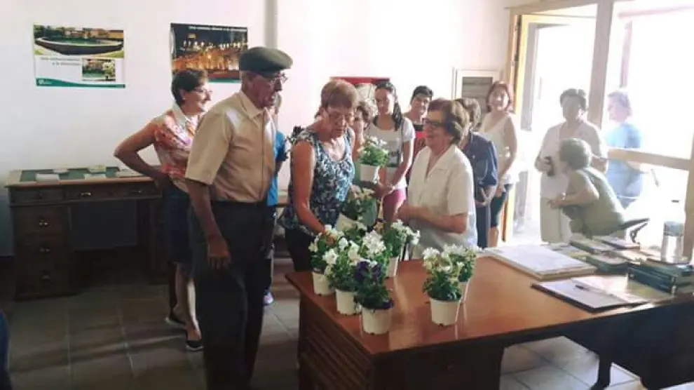 Los vecinos de Cedrillas recogen las flores repartidas por el Ayuntamiento de la localidad.