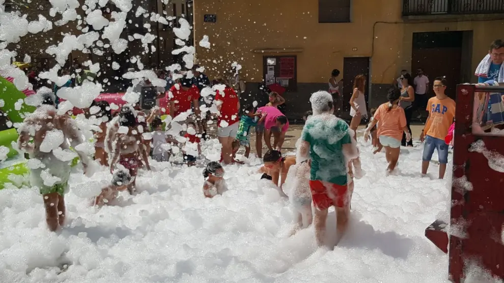 Los niños disfrutaron ayer del tobogán acuático y de la fiesta de la espuma en la calle de la Fuente.