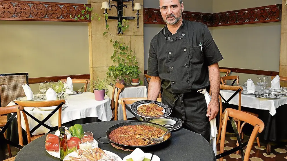 El jefe de cocina de Nuevo Rogelios en Zaragoza, Marcial Gabás, junto a la fideuá que prepara y sus ingredientes.