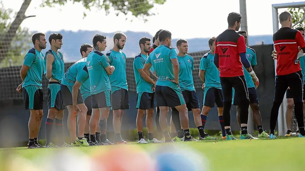 Los futbolistas del Huesca escuchan las explicaciones de los técnicos nada más arrancar la sesión de ayer en el Montearagón.