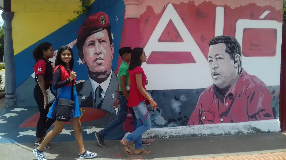 Jóvenes pasan ante un cartel de Chávez en la localidad venezolana de Sabaneta.