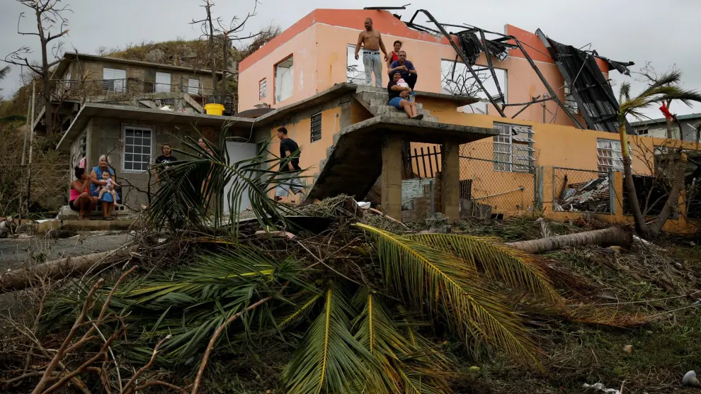 Los habitantes de una de las zonas afectadas por el paso del huracán María, en Puerto Rico, permanecen en el exterior de sus casas, que han sido dañadas por este.