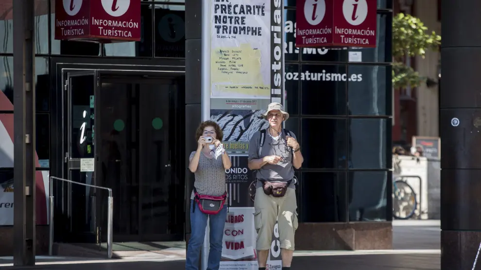 Dos turistas, a su salida de la oficina de información de la plaza del Pilar.