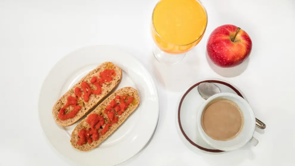 Un desayuno energético: una taza de café, leche o yogur, fruta y pan integral con tomate y aceite de oliva
