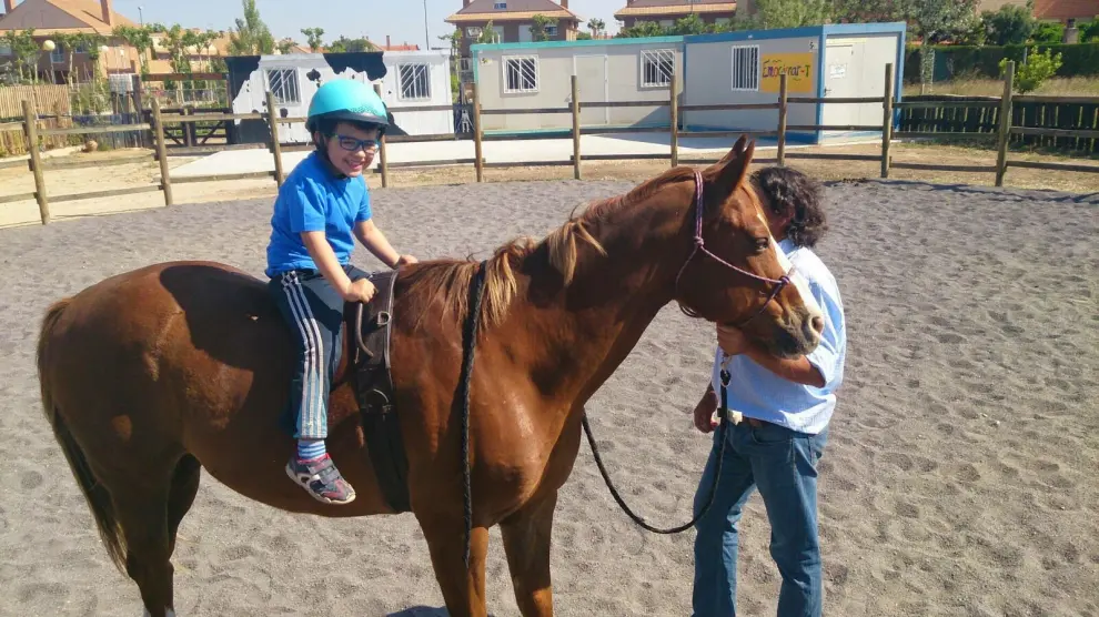 Un niño sobre un caballo disfruta de una sesión de hipoterapia en el centro de Aldeas Infantiles en Zaragoza.