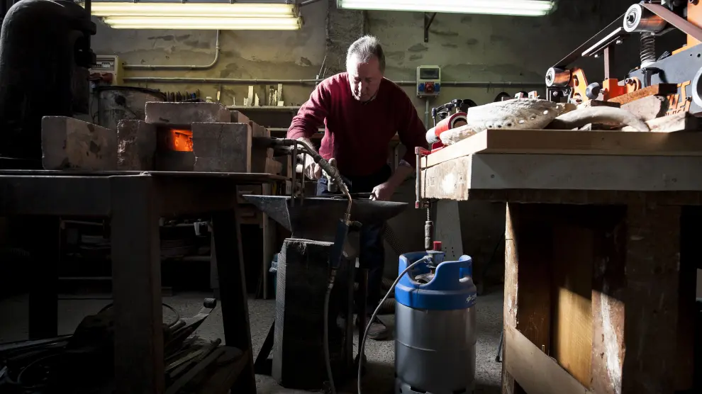 Román Sanz trabaja el acero después de calentarlo en su pequeña estructura de ladrillo, alimentada por dos sopletes.