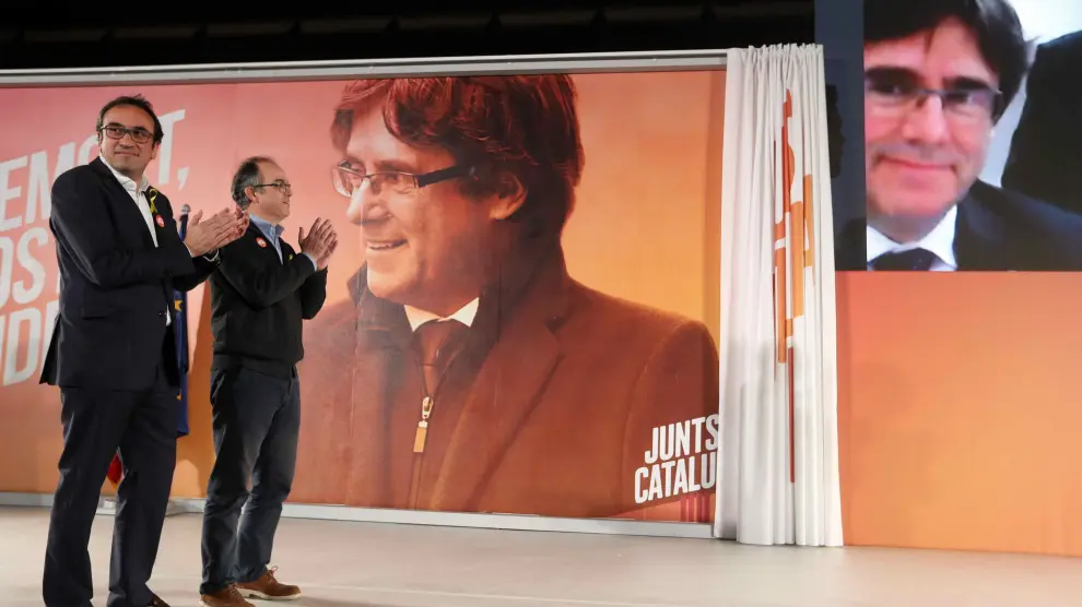 Los exconsellers y candidatos de JxSí Jordi Turull y Josep Rull (i) hablan por videoconferencia con el expresidente Puigdemont