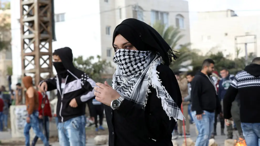 Una mujer observa a soldados israelíes durante una protesta.