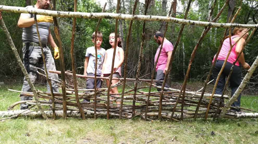 Construyendo un refugio con troncos y ramas, en la experiencia 'Superviviencia en familia', en Loarre.